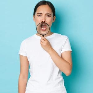 Portrait of funny and cute asian girl making announcement, searching for someone, shouting, holding magnifying glass over opened mouth with serious expression, calling for somebody.